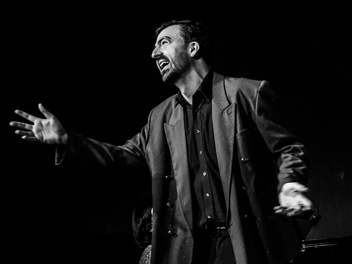 Alan Picol chantant sur scène, les bras ouverts